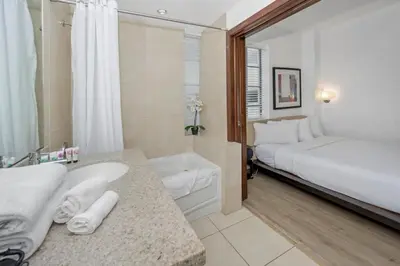 a white bathroom with a bed and a sink and a tub at Steps from the Ocean Comfy Studio with King Bed in Miami Beach