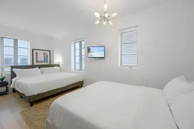 a white bedroom with two beds and a ceiling fan at Steps from the Ocean Comfy Studio with King Bed in Miami Beach