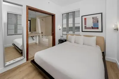 a bedroom with a large white bed and a bathroom at Steps from the Ocean Comfy Studio with King Bed in Miami Beach