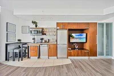 a kitchen with wooden cabinets and a stainless steel refrigerator at Stylish Studio in South Beach with Ocean Views in Miami Beach