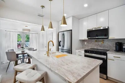 a kitchen with white cabinets and a large marble counter top at Chic Villa Nina 2 bedrooms 2 baths in Miami! in North Miami