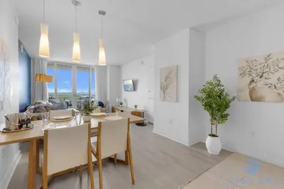 a dining room and living room with a table and chairs at Infinite Views - Private Balcony -Poolside Bliss Near the Beach in Hallandale Beach