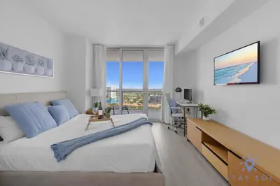 a bedroom with a bed and a desk with a view at Balcony with Infinite Views - Poolside Comfort in Hallandale Beach