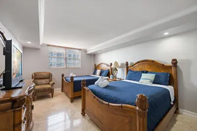 a bedroom with two beds and a tv and a chair at Entire Condominium in Sunny Isles in Sunny Isles Beach