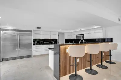 a kitchen with white cabinets and bar stools at Waterfront 3bed | Pool | 10min walk to Beach in Hallandale Beach