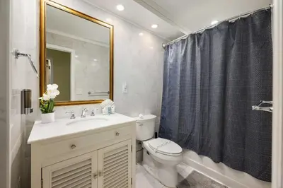 a bathroom with a sink and a toilet and a mirror at Bright Stylish 2BR Condo Stunning View Of Ocean in Sunny Isles Beach