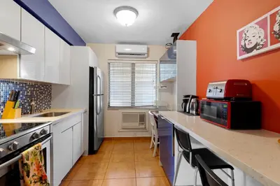 a kitchen with white cabinets and an orange wall at 1BR Studio Parking, Pet Friendly and BBQ Area in Hollywood