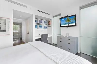 a white bedroom with a bed and a flat screen tv at Large Beach Suite Rooftop Pool by Convention Center in Miami Beach