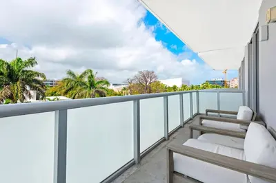 a balcony with white furniture and palm trees at Large Beach Suite Rooftop Pool by Convention Center in Miami Beach