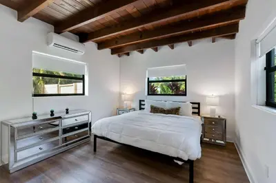 a bedroom with a white bed and two windows at Hidden Bungalow- Peaceful retreat BBQ and hot tub in Miami
