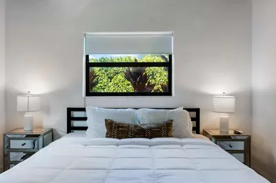 a bedroom with a large white bed with a window at Hidden Bungalow- Peaceful retreat BBQ and hot tub in Miami