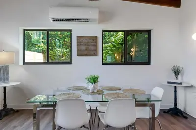 a dining room with a glass table and white chairs at Hidden Bungalow- Peaceful retreat BBQ and hot tub in Miami