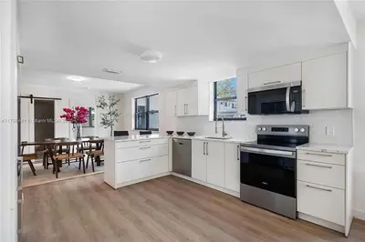 a kitchen with white cabinets and a dining room with a table at Oceanview Crespi Villa in Miami Beach