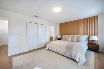 a bedroom with a white bed and a wooden wall at Oceanview Crespi Villa in Miami Beach