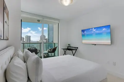 a white bedroom with a bed and a large window at Brickell River Views- modern amenities in the city in Miami