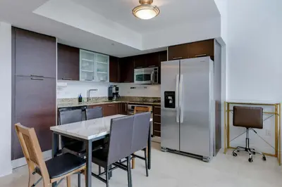 a kitchen with a table and a stainless steel refrigerator at Brickell River Views- modern amenities in the city in Miami