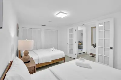 a white bedroom with a bed and a lamp at 4BR Home Heated Pool And BBQ short drive Beach! in Hollywood