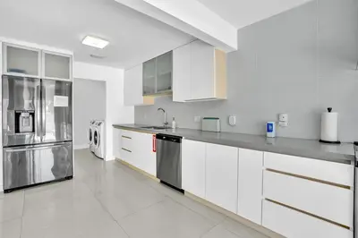 a kitchen with white cabinets and a stainless steel refrigerator at 4BR Home Heated Pool And BBQ short drive Beach! in Hollywood