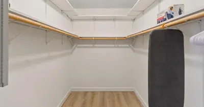a walk in closet with white walls and wood floors at Boho Style 5 BR 2,5 BT Heated Pool Fit 14 in Miami