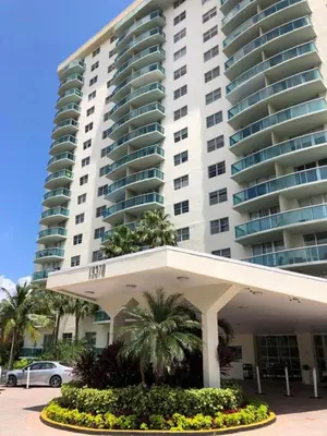 a large building with a palm tree in front of it at Beatiful apartment 2nd Floor - SRT 3143 in Sunny Isles Beach