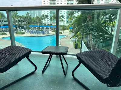 two chairs and a table on a balcony with a pool at Beatiful apartment 2nd Floor - SRT 3143 in Sunny Isles Beach