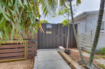 a fence in front of a house with palm trees at Fort Lauderdale Studio Near Beaches and Downtown in Fort Lauderdale