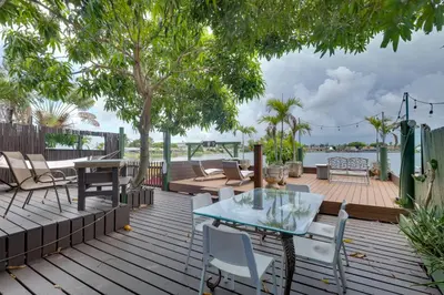 a patio with a glass table and chairs on a deck at Lakefront Getaway with Dock Near Las Olas Beach in Fort Lauderdale