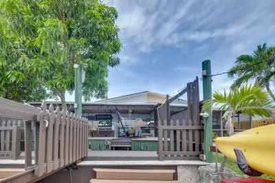 a wooden fence in front of a house with trees at Lakefront Getaway with Dock Near Las Olas Beach in Fort Lauderdale