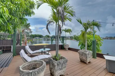 a deck with palm trees and a table and chairs at Lakefront Getaway with Dock Near Las Olas Beach in Fort Lauderdale