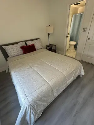 a bedroom with a white bed with a red pillow at Room w Private Entrance near Airport, Dolphin Mall & FIU in Miami