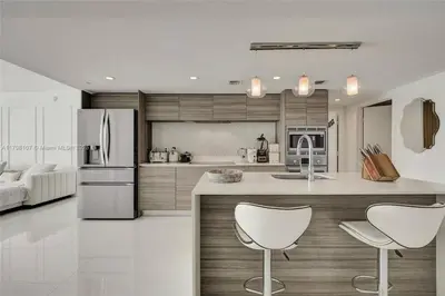 a kitchen with a refrigerator and two white chairs at Beachfront Bliss in Miami in Miami Beach