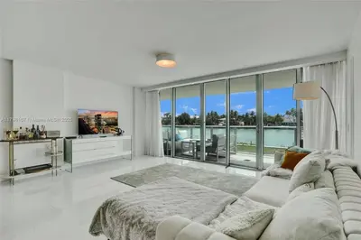 a white living room with a couch and a large window at Beachfront Bliss in Miami in Miami Beach