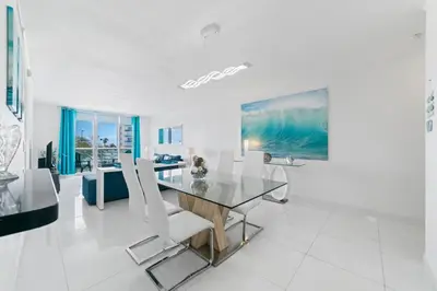 a dining room with a glass table and white chairs at Ocean Wind - Luxury Beachfront Condo with Pool & Gym in Hollywood