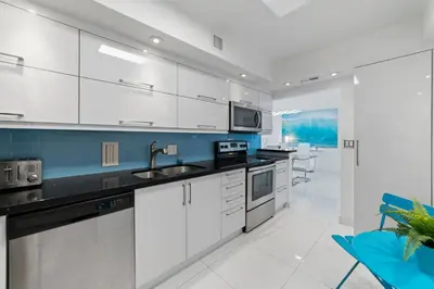 a kitchen with white cabinets and blue accents at Ocean Wind - Luxury Beachfront Condo with Pool & Gym in Hollywood