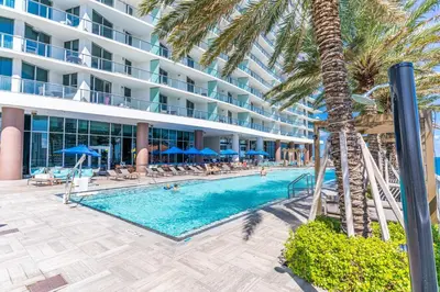 a swimming pool with a palm tree and a hotel at Luxury Living on the Beach with Resort Amenities in Hollywood