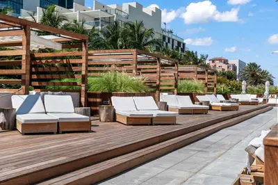 a row of white lounge chairs on a wooden deck at Oasis on the Beach - For 4 in Miami Beach
