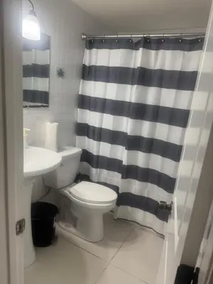 a bathroom with a toilet and a shower curtain at La sama Wynwood in Miami