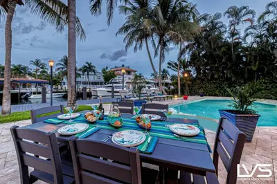 a table with plates of food on it next to a pool at Villa Marea - Heated Pool Spa & Water Views in Fort Lauderdale