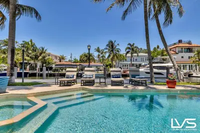 a swimming pool with chairs and palm trees at Villa Marea - Heated Pool Spa & Water Views in Fort Lauderdale