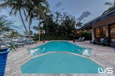 a swimming pool in a resort with palm trees at Villa Marea - Heated Pool Spa & Water Views in Fort Lauderdale