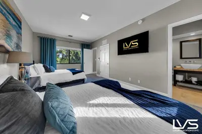 a bedroom with two beds and a tv on the wall at Villa Marea - Heated Pool Spa & Water Views in Fort Lauderdale