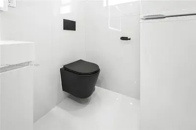 a bathroom with a black toilet in a white wall at Bayside Bliss on Marseille in Miami Beach