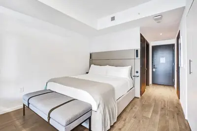 a white bedroom with a large bed and a bench at 4704 Lux Miami Studio City Bay Views in Miami