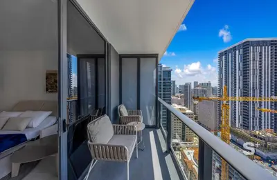 a balcony with a bed and chairs on a building at Modern 1-BD Condo in Downtown Miami City Views in Miami