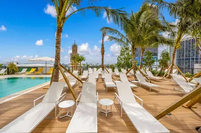 a row of white lounge chairs next to a pool at Modern 1-BD Condo in Downtown Miami City Views in Miami