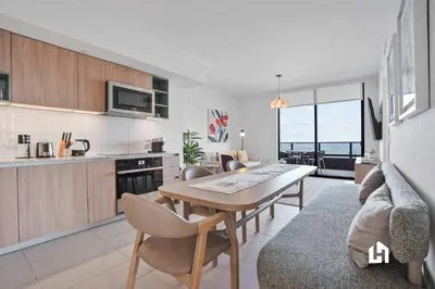 a kitchen and living room with a table and chairs at Stylish Sky-High Condo with Pool and Gym in Miami