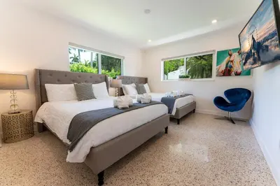 a bedroom with a large bed and a blue chair at TROPICAL Villa with POOL in Private Island in Miami Beach
