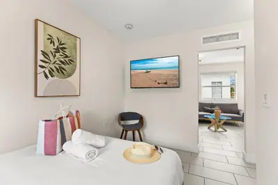 a white bedroom with a bed and a chair at Byron Avenue Suites in Miami Beach