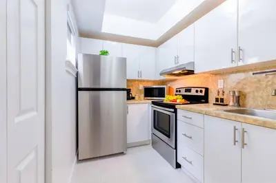a kitchen with white cabinets and a stainless steel refrigerator at Beachy Living |Sleep 8 Best Location | BBQ & Patio in Miami