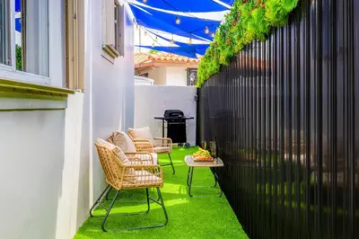 a patio with two chairs and a table with green grass at Beachy Living |Sleep 8 Best Location | BBQ & Patio in Miami